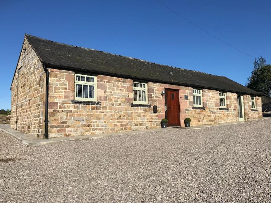 um edifício de tijolos com uma porta vermelha numa estrada de cascalho em 2 Bed Stylish Peak District Cottage Barn Near Alton Towers, Polar Bears, Chatsworth House em Waterfall