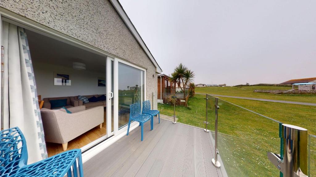 a balcony with blue chairs and a couch on a house at F60 Atlantic View, Riviere Towans in Hayle
