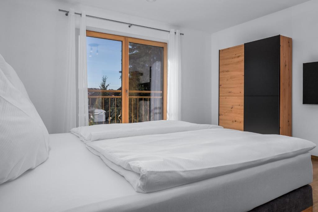 a white bedroom with two beds and a window at Ferienhäuser Buchenweg in Bodenmais