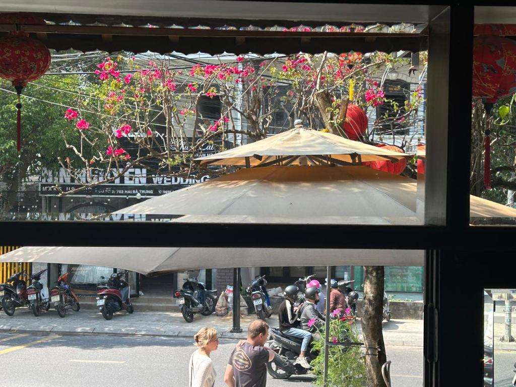 un grupo de personas de pie fuera de un edificio con un paraguas en Vang Anh Homestay Hoi An, en Hoi An