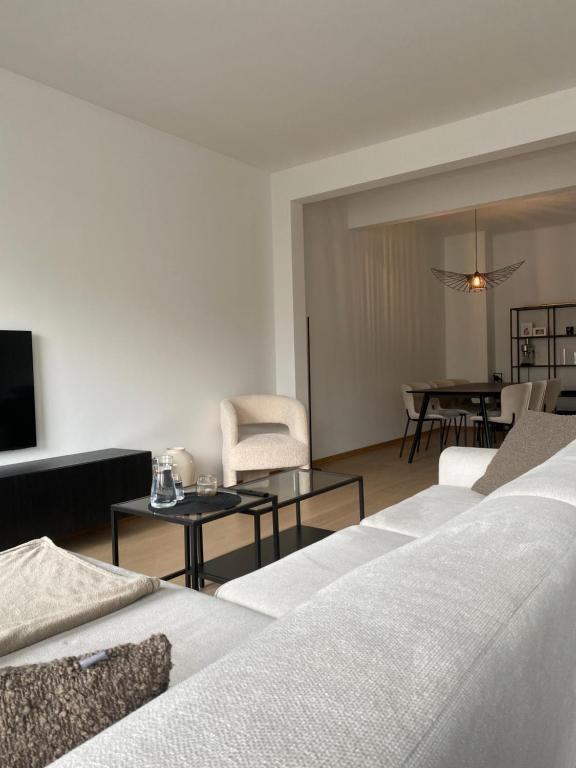 Il comprend un salon doté d'un mobilier blanc et une salle à manger. dans l'établissement Cosy Apartment near Antwerp, à Mortsel