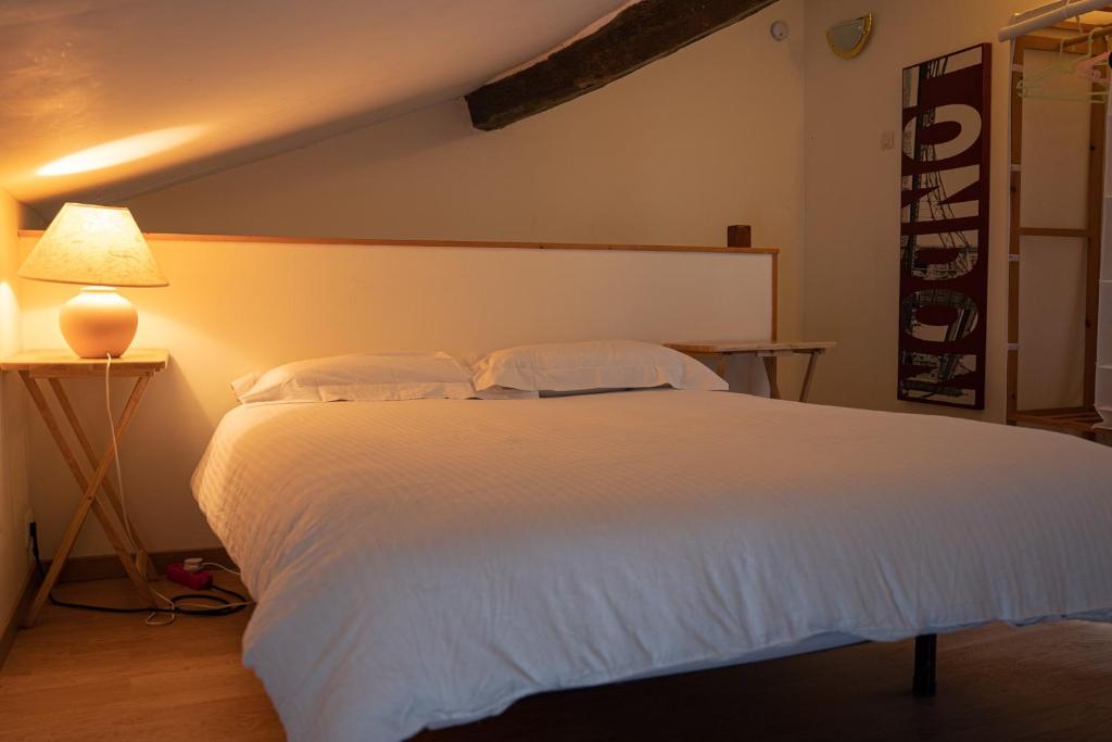 een slaapkamer met een wit bed en een lamp bij L'appartement à la campagne in Vermenton