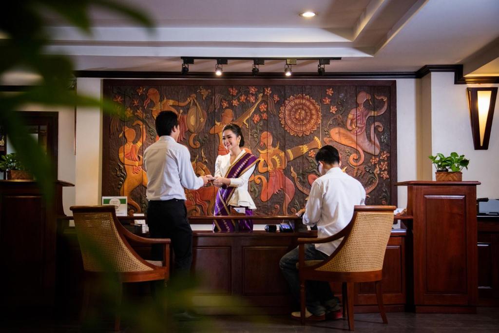 a group of people sitting at a bar in a restaurant at Lao Orchid Hotel in Vientiane
