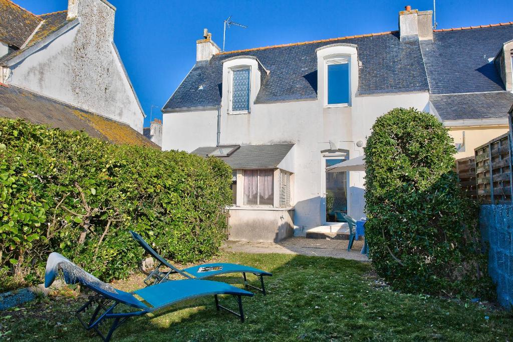 une cour avec deux bancs bleus devant une maison dans l'établissement À 100m de la plage ! Maison pour 6 à Penmarch, à Penmarcʼh