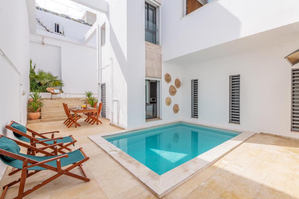 a swimming pool in a house with chairs and a table at Villa Lord Hammon in Gammarth