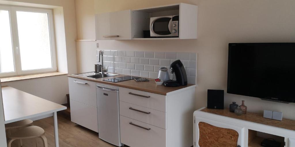 a kitchen with white cabinets and a flat screen tv at comme à la maison in Clonas-sur-Varèze