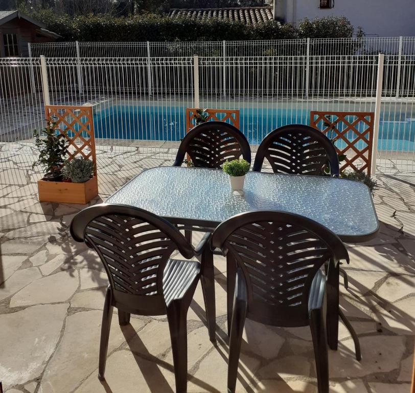 una mesa con cuatro sillas y una mesa con una planta. en maison mitoyenne avec piscine Un moment chez Diane, en Grasse