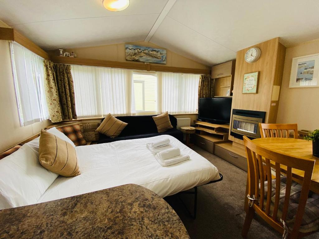 a bedroom with a large bed and a living room at Older Style Caravan Pebble Bank T10 in Wyke Regis