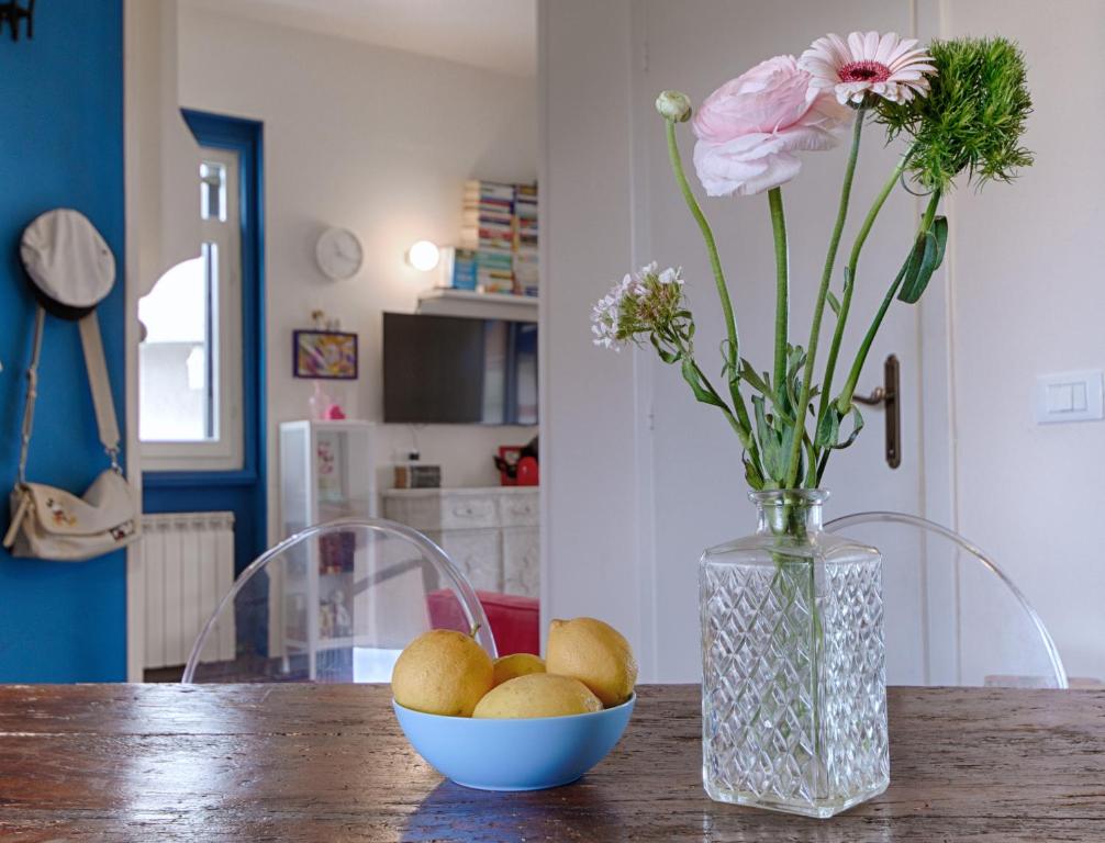 um vaso com flores e uma taça de fruta numa mesa em Il nido sul mare - Affitti Brevi Italia em Torre del Lago Puccini