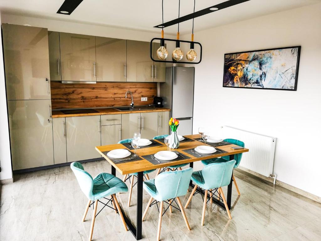 eine Küche mit einem Holztisch und blauen Stühlen in der Unterkunft NOVA House Apartments in Delniţa
