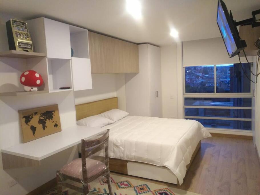 Un dormitorio con una cama, un escritorio y un televisor. en Hermoso mini apartamento en el corazón de Bogotá, en Bogotá