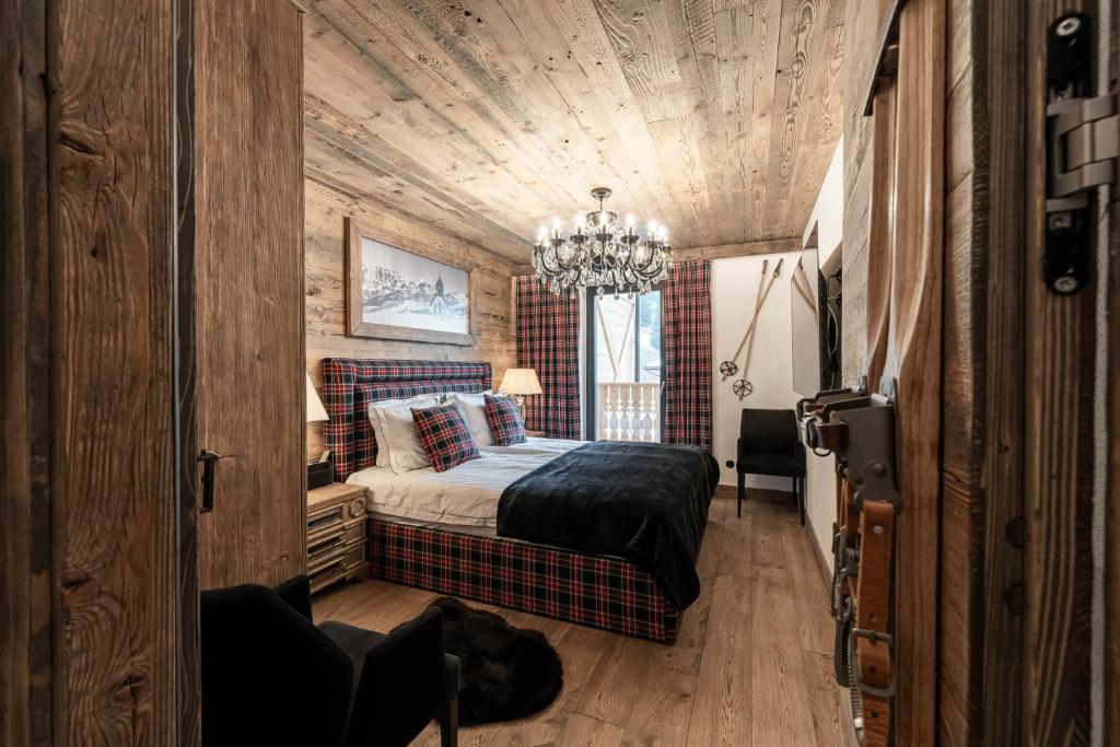 1 dormitorio con cama y lámpara de araña en Belvedere Elite, en Canazei