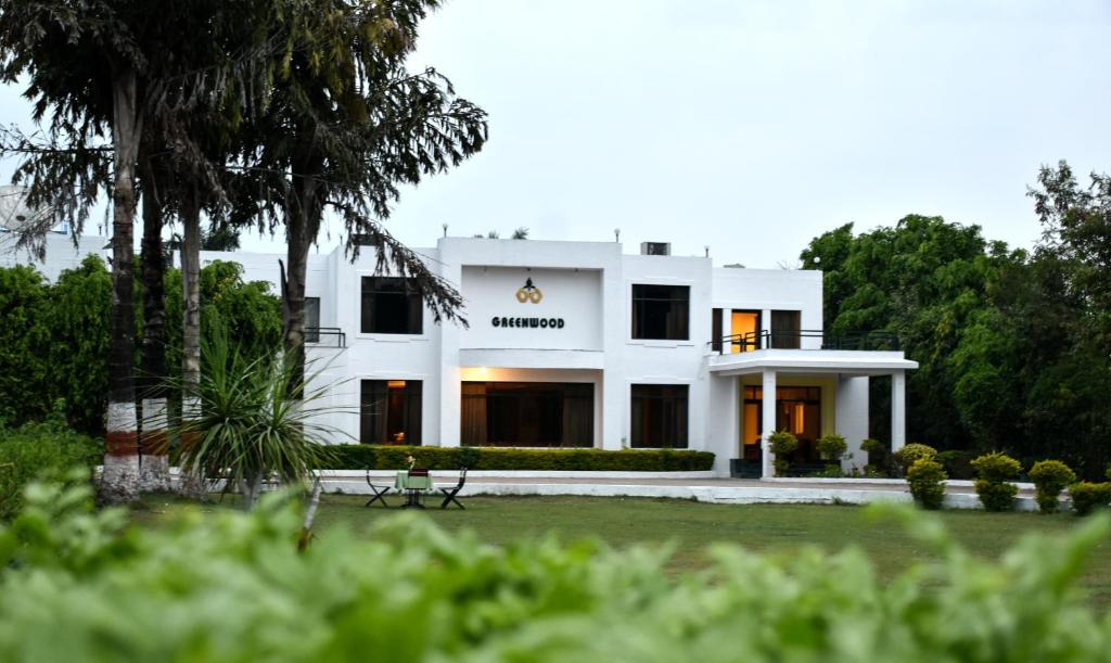 a white house with trees in the foreground at Greenwood Hotel in Khajurāho