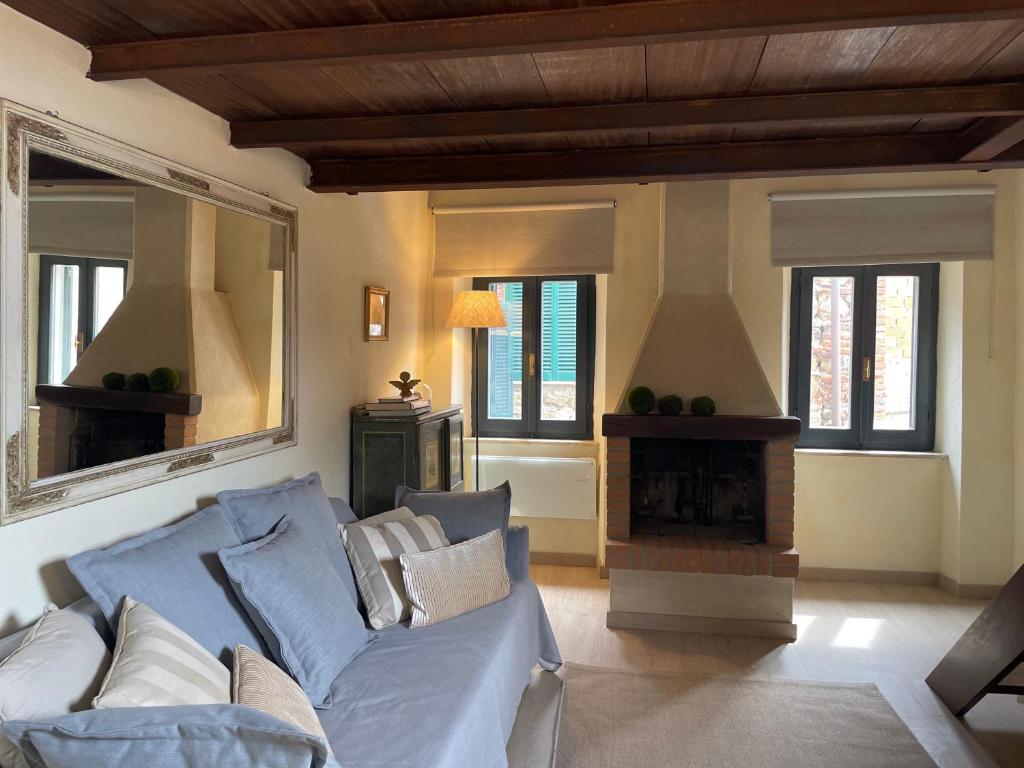 Saturnia Country Loft Montemerano ( Terme a 6 km) في مونتيميرانو: غرفة معيشة مع أريكة زرقاء ومدفأة