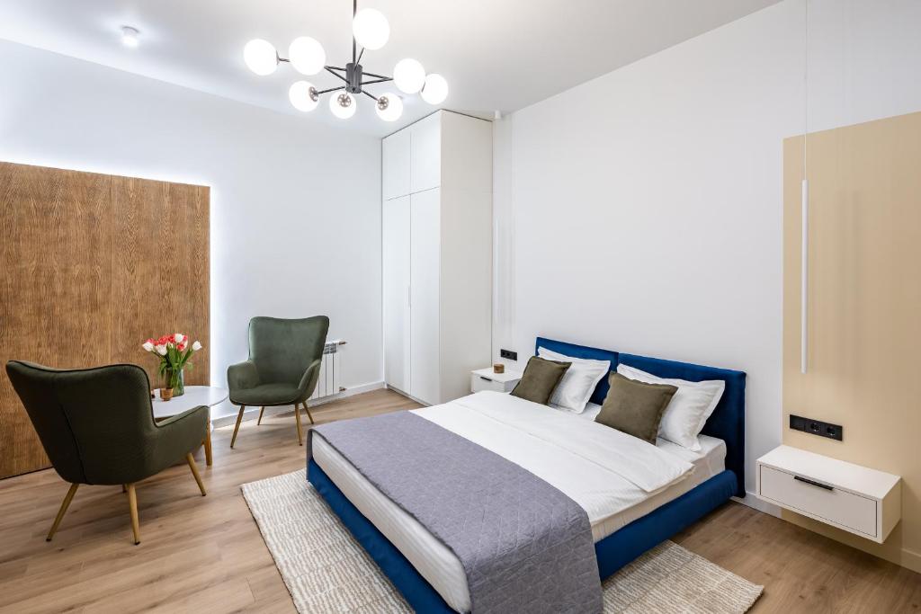 a bedroom with a blue bed and two chairs at MONTENEL Apartel in Lviv