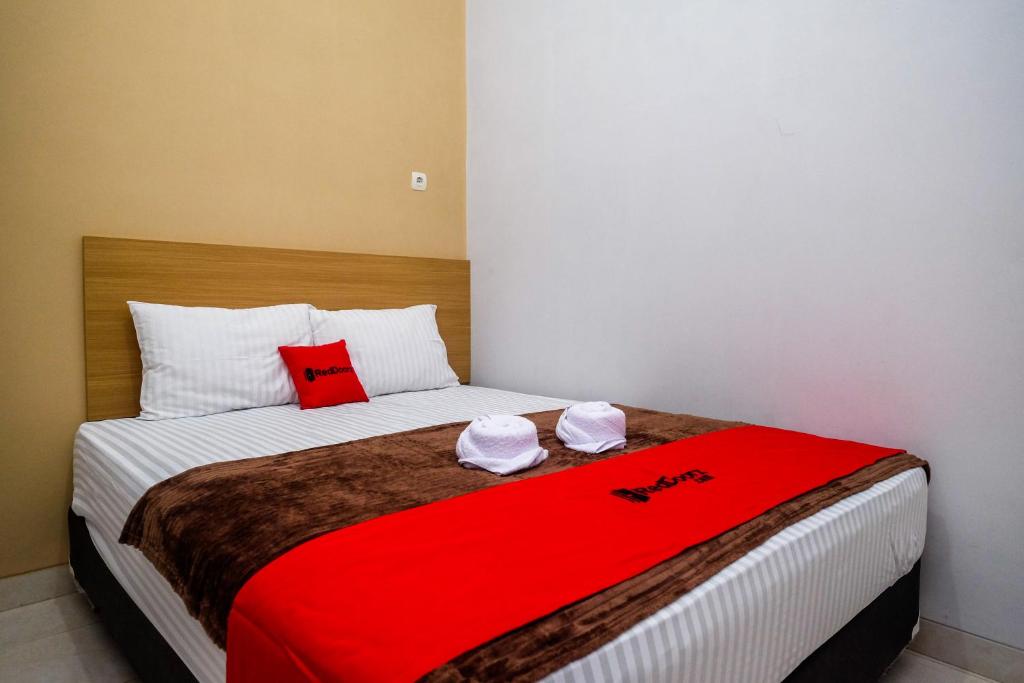 um quarto com uma cama com um cobertor vermelho em RedDoorz Syariah near Perempatan Kartasuro em Surakarta