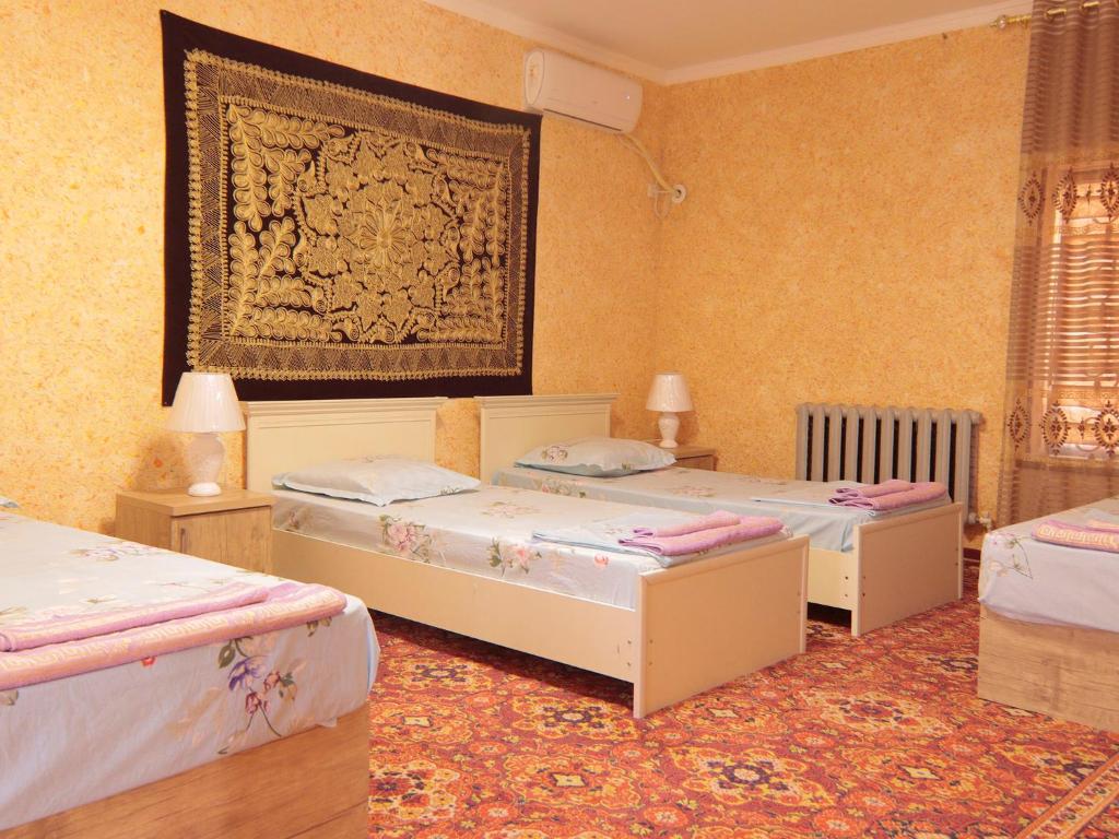 a bedroom with three beds and a painting on the wall at LION Guest House in Bukhara