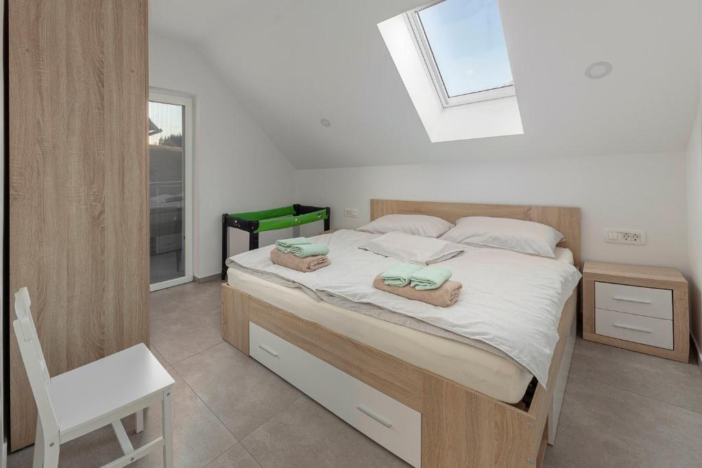 a bedroom with a bed with a chair and a window at Apartments Linda in Brezje