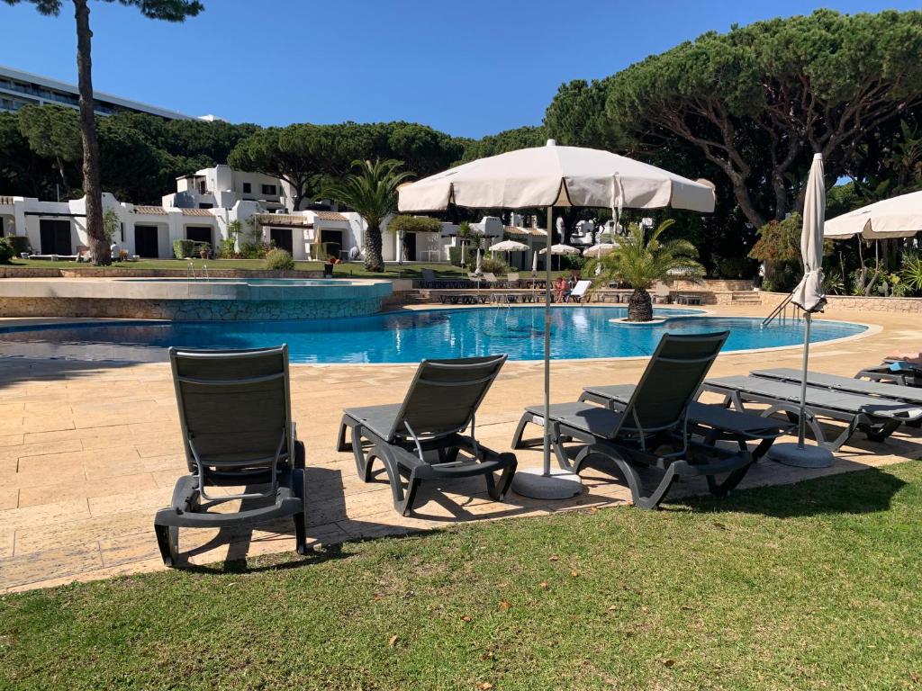 a group of chairs and umbrellas next to a pool at Piece of Paradise @ Balaia Golf Village, Albufeira, PORTUGAL - 4 STAR in Albufeira