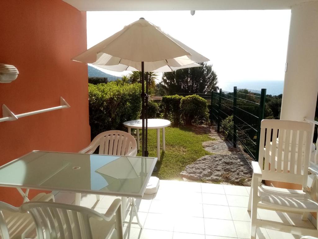 a patio with a table and chairs and an umbrella at Studio 4 Pers Vue Mer Cap Esterel in Saint-Raphaël