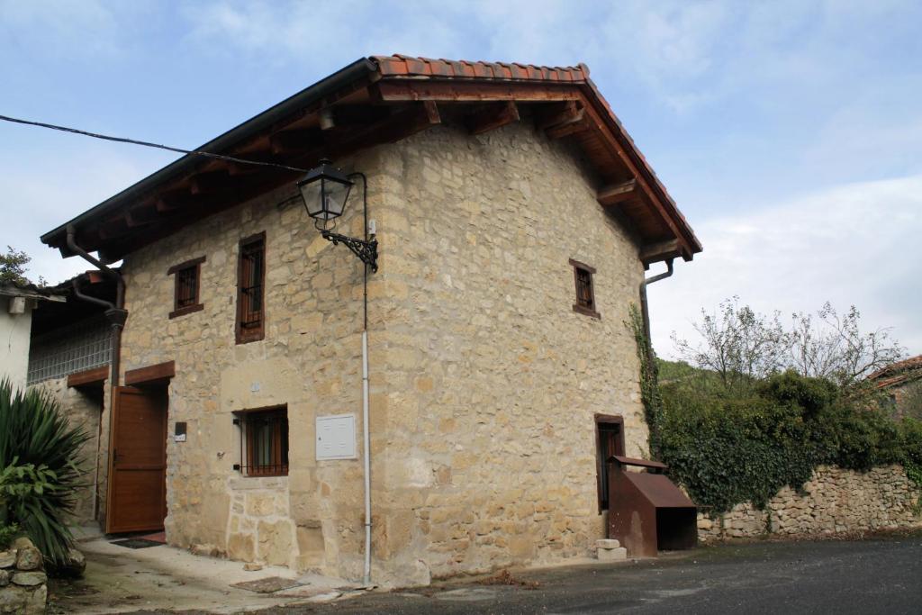 een oud stenen gebouw met een koperen dak bij El horno Albergue Manzanos in Manzanos