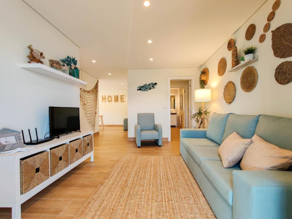 sala de estar con sofá azul y TV en Pé Na Duna - beachfront apartment, en Viana do Castelo