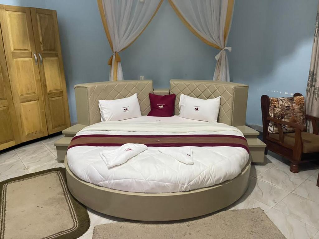 una camera da letto con un grande letto con lenzuola bianche e cuscini rossi di Dreamwood suites Mbarara a Mbarara