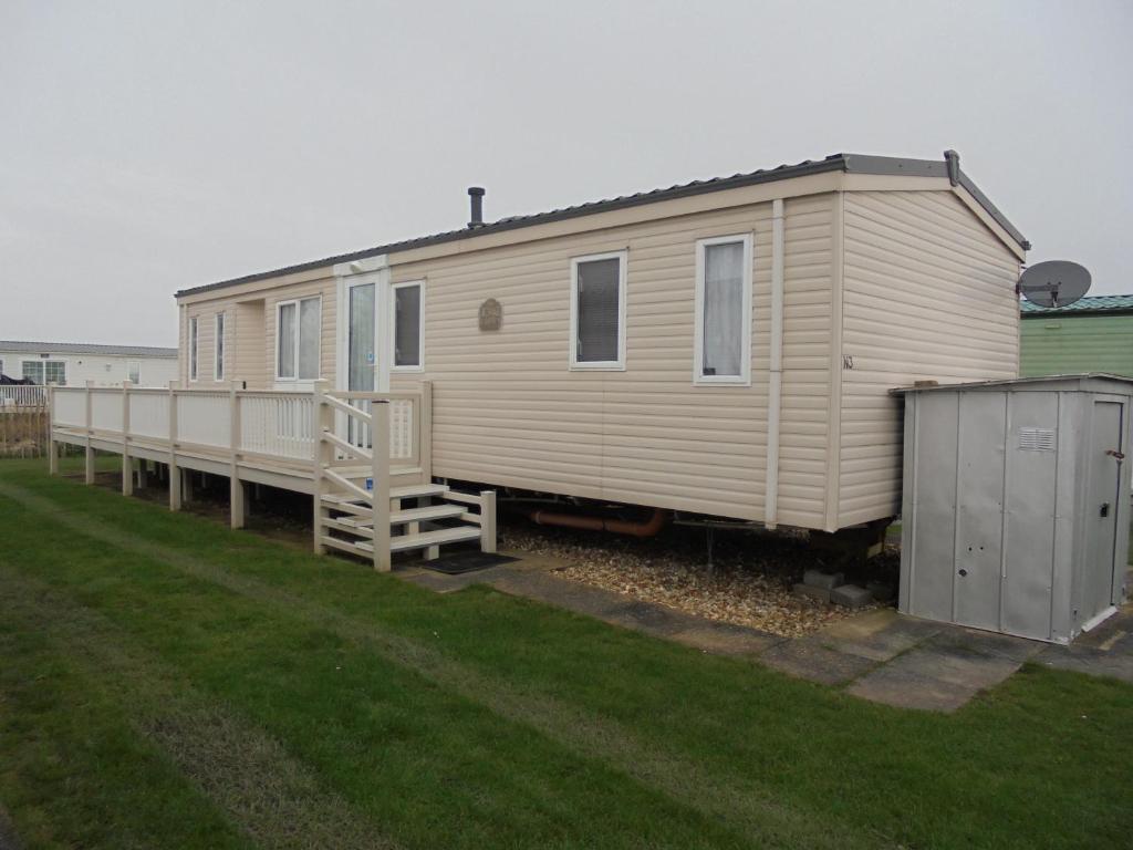 a large white mobile home sitting in a yard at The Chase Topaz Super 4 Berth panel heated Wrap around veranda in Ingoldmells