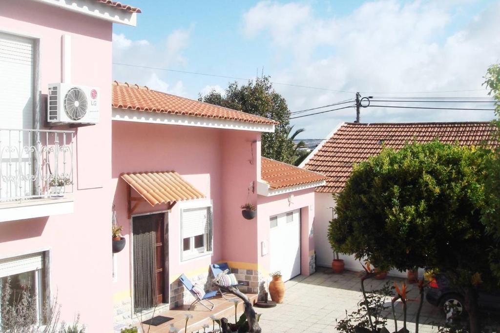 uma casa rosa com um pátio em frente em Casa Oleandros na Lourinhã