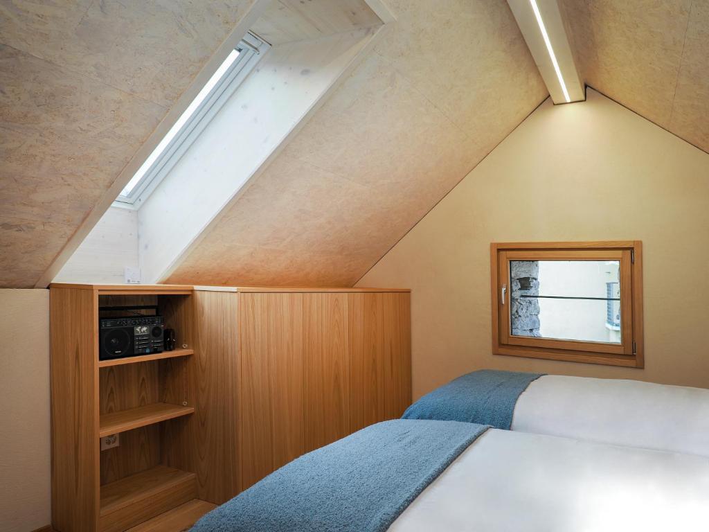 - une chambre mansardée avec 2 lits et une fenêtre dans l'établissement Rustico Mulino1 - Fully Renovated Near Locarno and Ascona, à Minusio