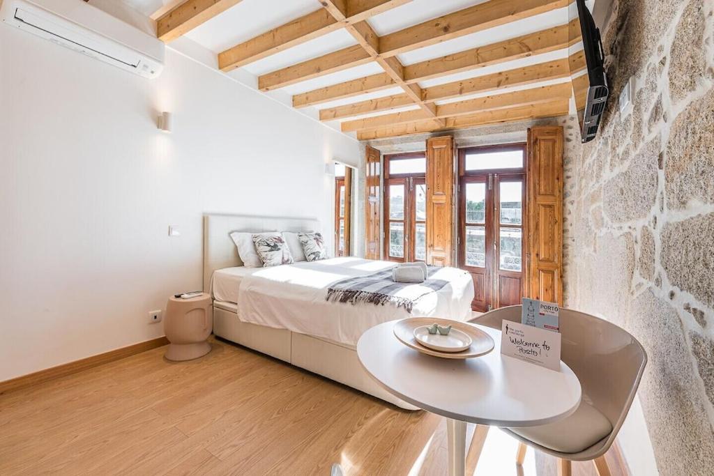 a bedroom with a white bed and a table at GuestReady - Miragaia Stone Studio 2T in Porto