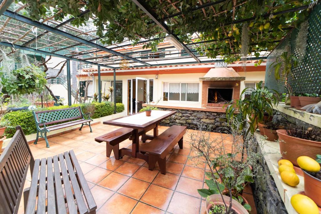 patio ze stołem, ławkami i kominkiem w obiekcie PineHouse w mieście Curral das Freiras