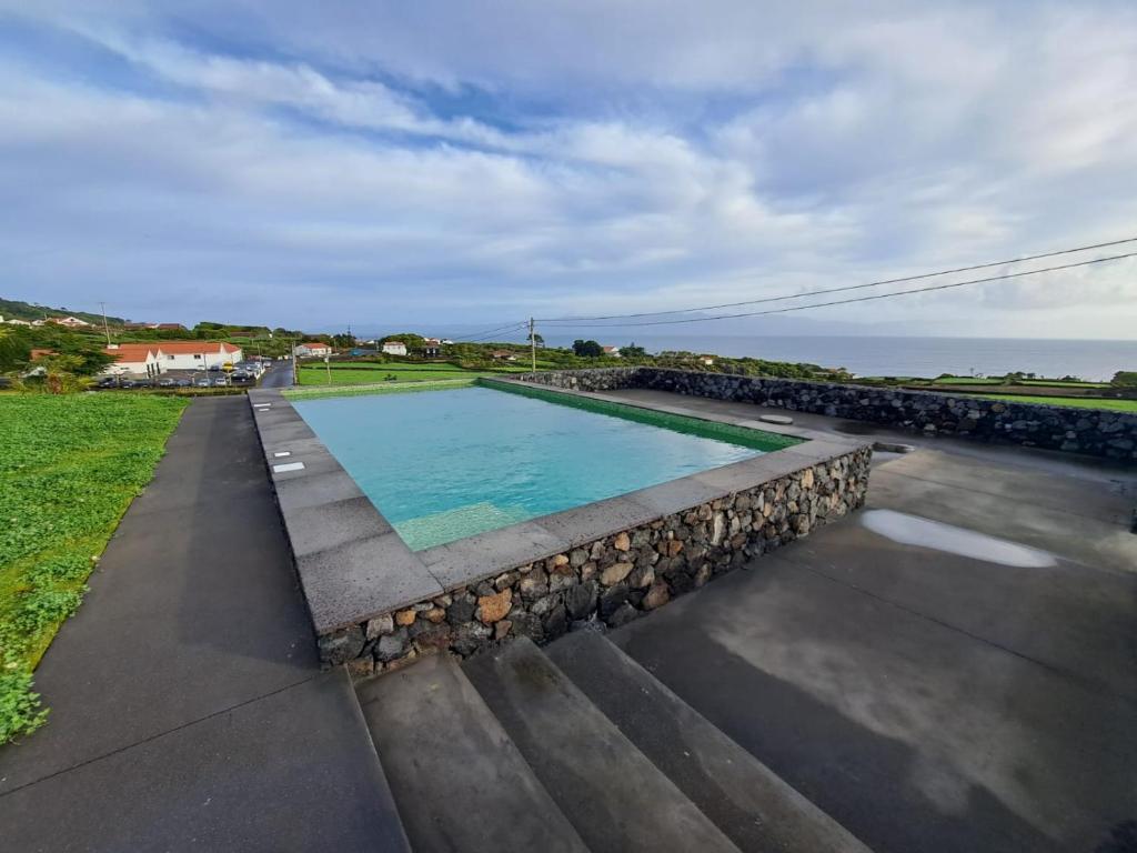 uma piscina com pedras ao redor junto ao oceano em Casas da Prainha C em Companhia de Baixo