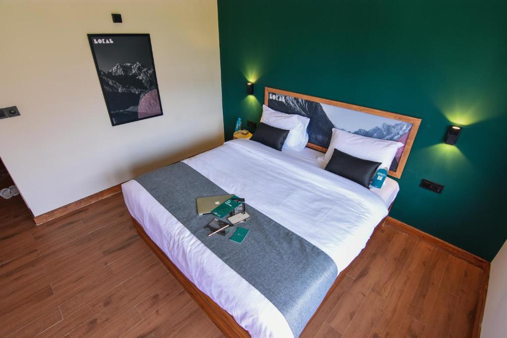 a bedroom with a large bed with a green wall at LOKAL Rooms x Skardu (Mountain View) in Skardu