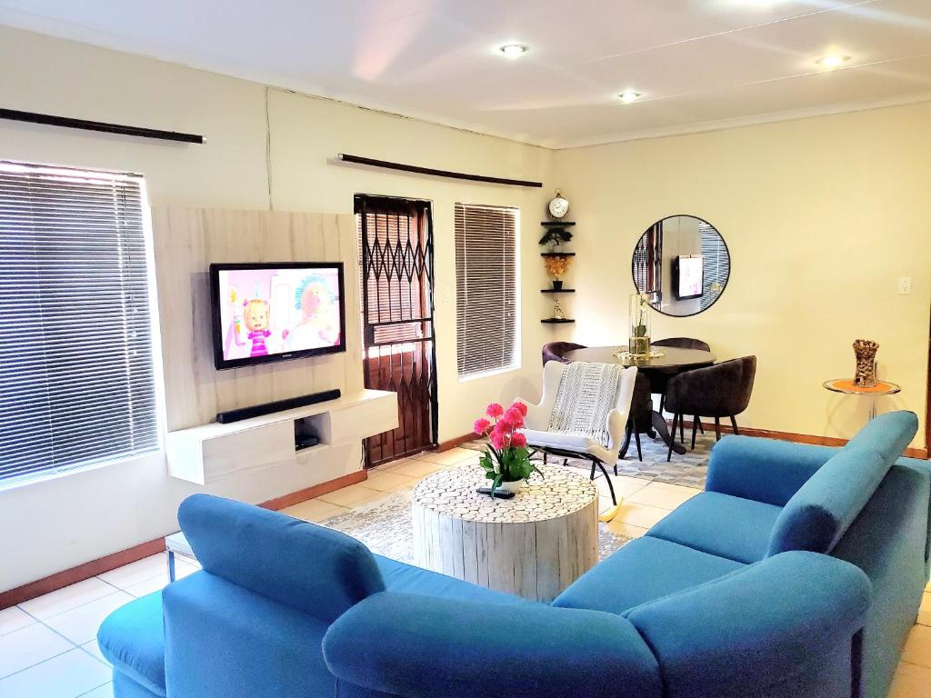 a living room with blue couches and a tv at Mnqobi Lifestyle Apartments in Nelspruit