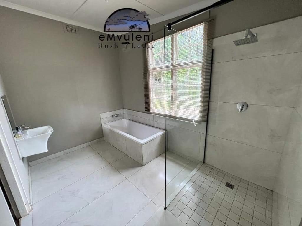 a bathroom with a shower and a toilet and a sink at Emvuleni Bush Lodge in Pietermaritzburg