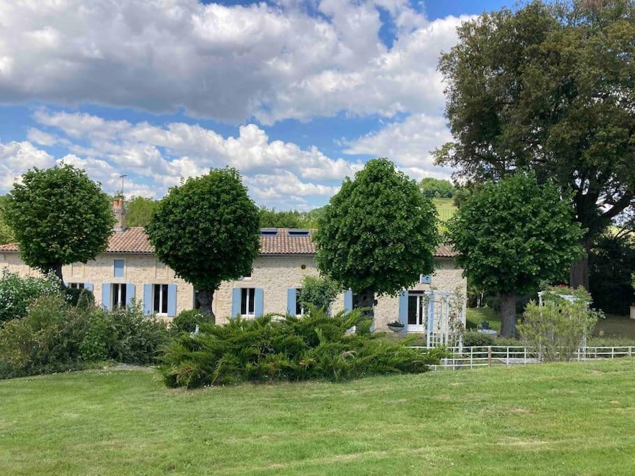 a building with trees in front of a field at Domaine sur les coteaux de Loupiac in Loupiac-de-Cadillac