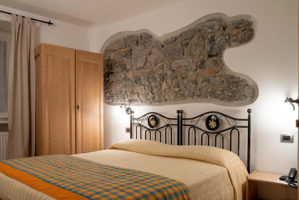 a bedroom with a bed with a stone wall at Garnì Centrale in Roncone