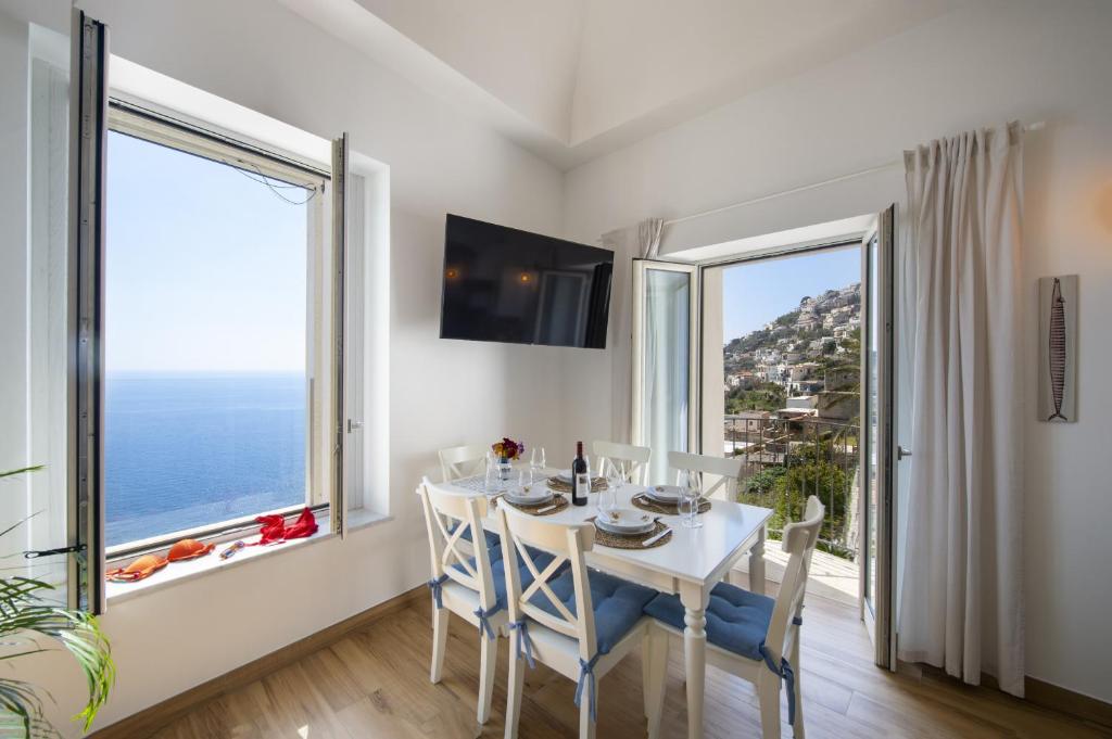 een eetkamer met een tafel en stoelen en een groot raam bij Casa Madonna del Mare in Praiano