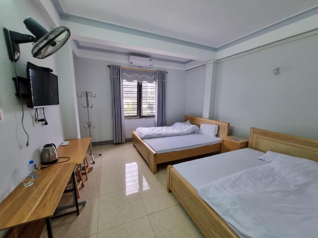 een kamer met 2 bedden, een bureau en een televisie bij NHÀ NGHỈ T&T in Dồng Văn