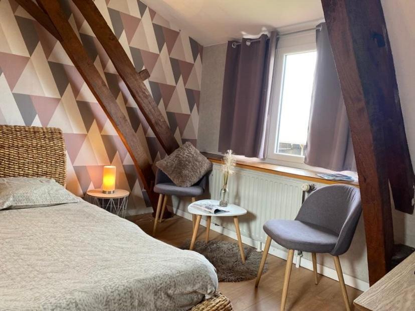 een slaapkamer met een bed en 2 stoelen en een raam bij Chambres dhotes a la ferme in Forest-Montiers