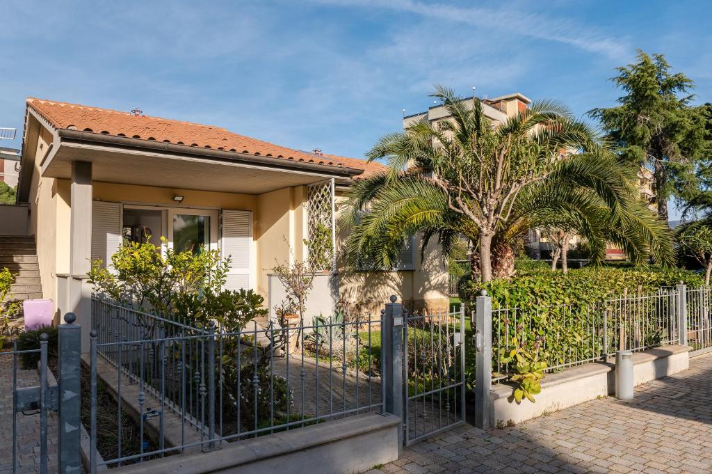 a house with a fence and a palm tree at Casa Pineta in Follonica