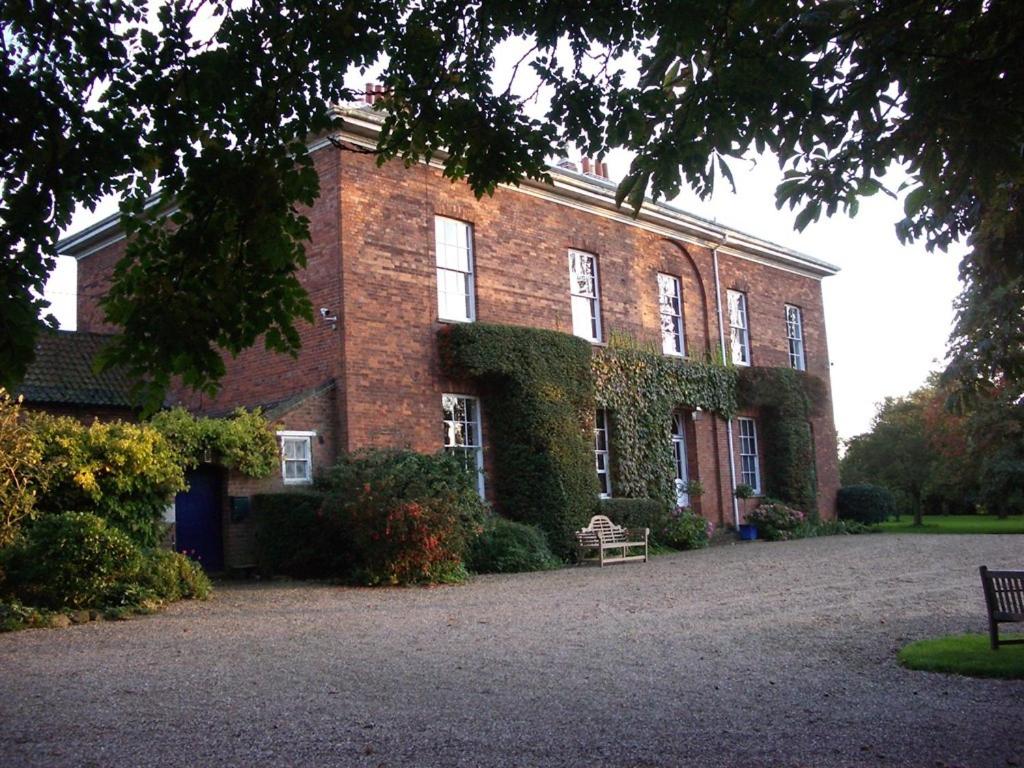 a large brick building with ivy growing on it at Glebe House Muston in Muston