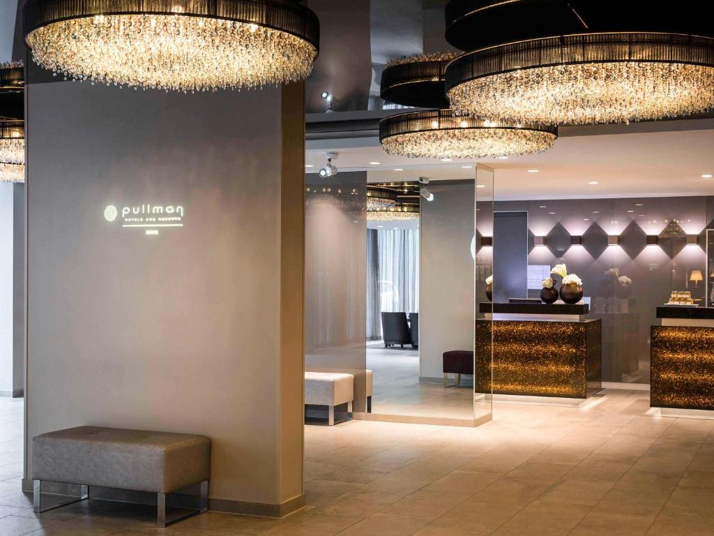 a lobby with chandeliers and a bench in a store at Pullman Munich in Munich