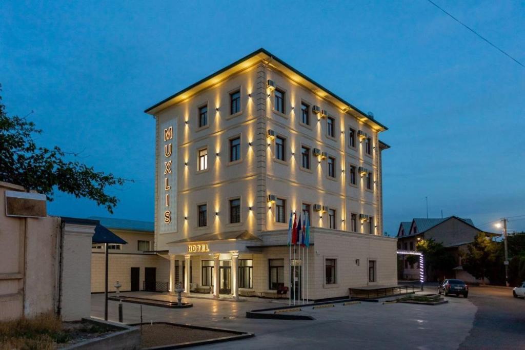een groot wit gebouw met verlichting bij Muxlis Hotel in Tasjkent