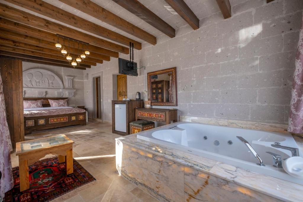 a large bathroom with a tub and a bedroom at Underground Cave Suites Hotel in Goreme