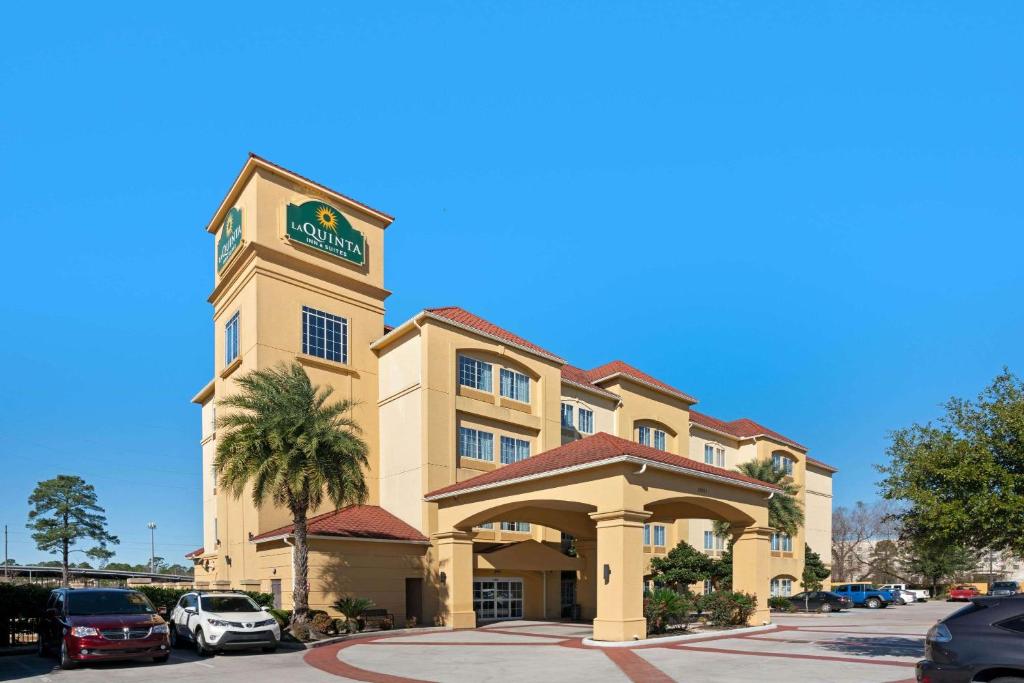 a hotel building with a clock tower in a parking lot at La Quinta by Wyndham Houston IAH Bush Intl Airport E in Humble