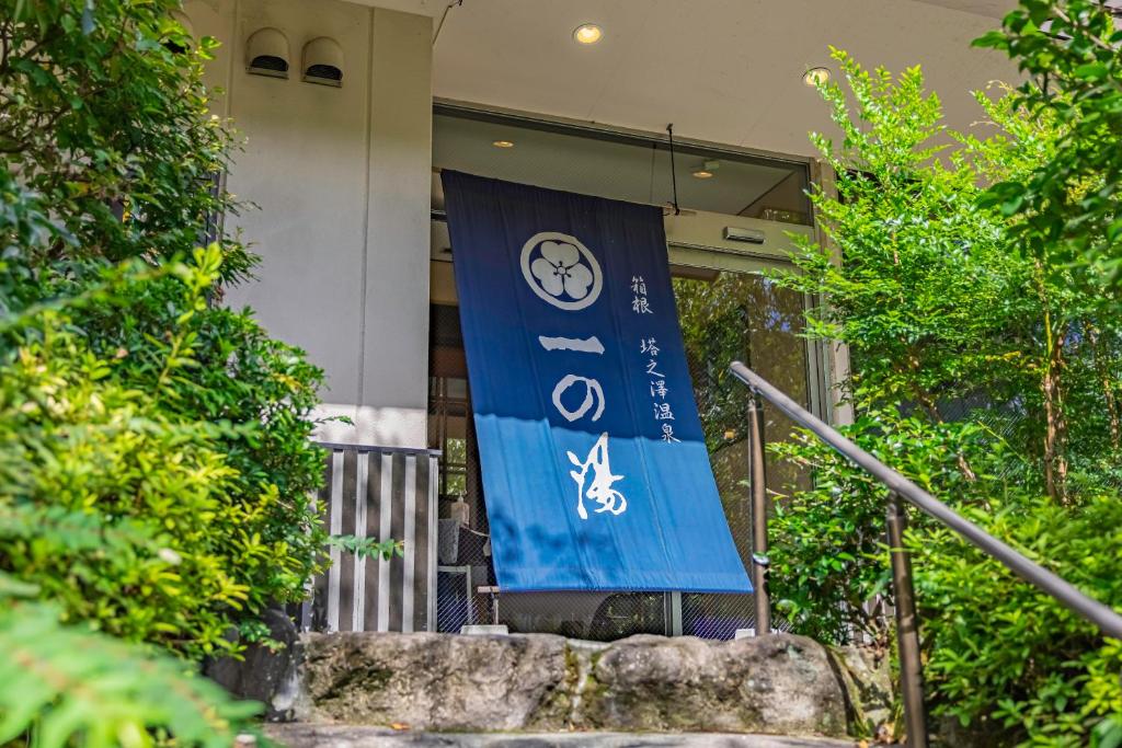 uma bandeira em frente a um edifício com árvores em Ichinoyu Shinkan em Hakone