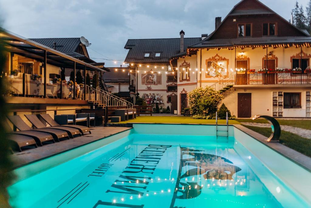 a villa with a swimming pool in front of a house at Hotel Vedmezhyi Dvir in Bukovel