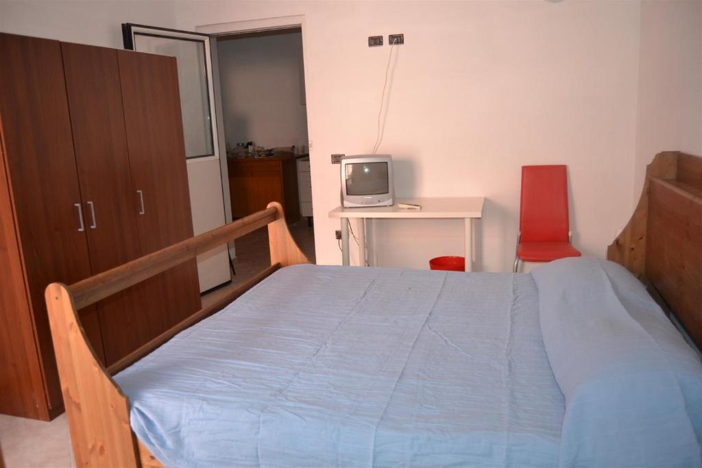 1 dormitorio con 1 cama y escritorio con TV en B&B La tarentilla, en Lizzano